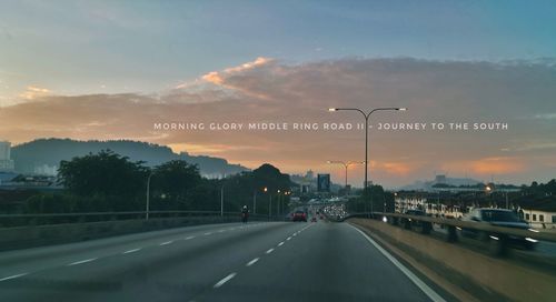 Road passing through city during sunset