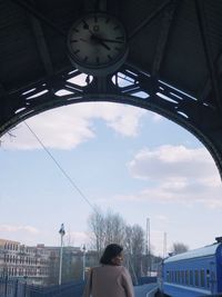 Rear view of woman standing against sky in city