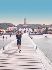 Rear view of woman walking on pier against clear sky