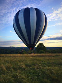 Hot air balloons on field against sky during sunset