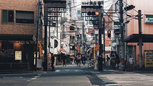 People walking on road against buildings in city