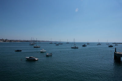 Boats sailing in sea against clear blue sky