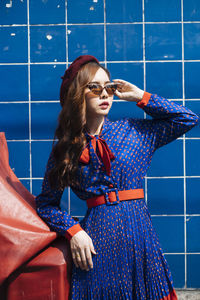 Young woman standing against blue wall