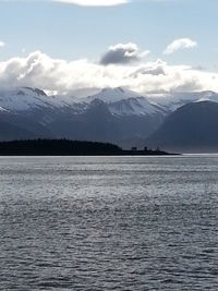 Scenic view of sea and mountains against cloudy sky