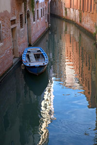 High angle view of nautical vessel moored in canal amidst buildings