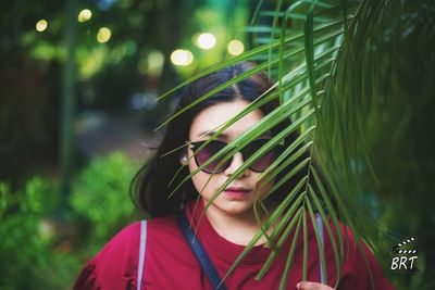 Portrait of young woman against tree