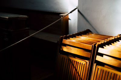 Close-up of folded wooden chairs against white wall