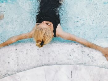 High angle view of mid adult woman with arms outstretched swimming in pool