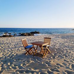 Deck chairs on beach against clear sky