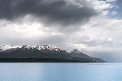 Gloomy landscape of new zealand southern alps and lake pukaki with blue sky and clouds.