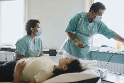 Surgeons in masks examining female patient in hospital