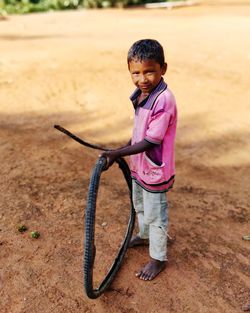 Cute boy with tire standing on land