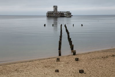Wooden posts on beach against sky.old torpedo house