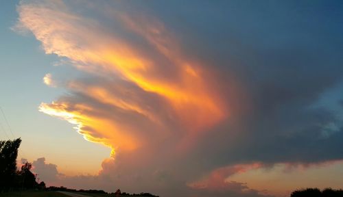 Silhouette landscape against cloudy sky during sunset