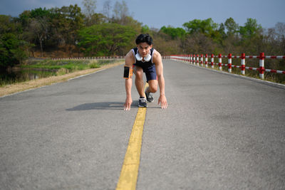 Full length of young woman exercising on road