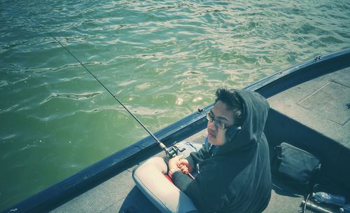 High angle view of man fishing while sitting in boat at sea