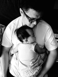 High angle view of daughter sleeping on father chest at home