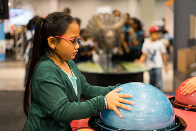 Side view of girl touching tesla ball on table