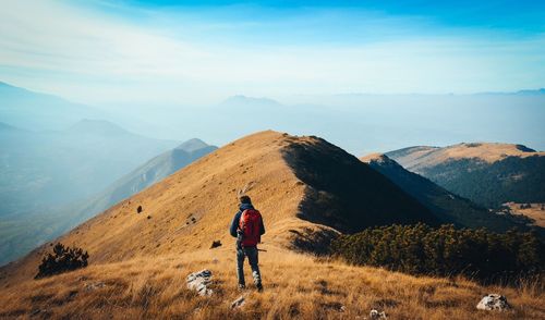 Rear view of man standing on mountain against sky