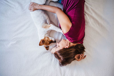 High angle view of woman with dog lying down on bed