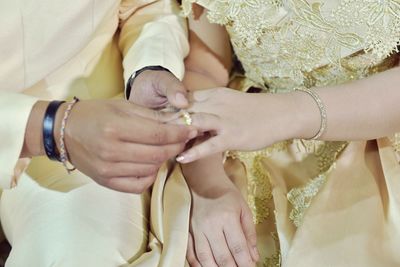 Close-up of bridegroom inserting wedding ring in bride finger
