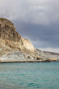 Scenic view of sea by rock formation against sky