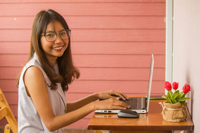 Portrait of young woman using laptop at table