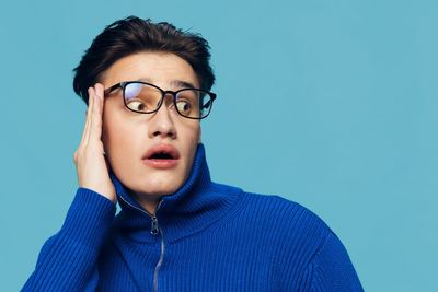 Portrait of young woman against blue background