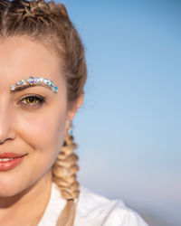 Close-up portrait of a smiling young woman against blue sky