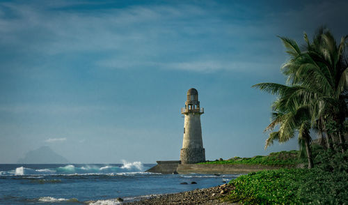 Lighthouse by sea against sky