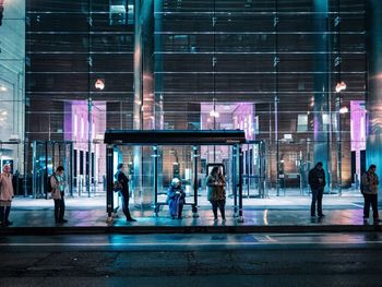 People walking on illuminated street in city at night