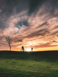 Silhouette people on field against sky during sunset