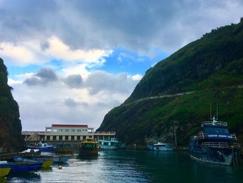 Boats moored at lake against cloudy sky