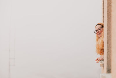 Woman looking through window against clear sky