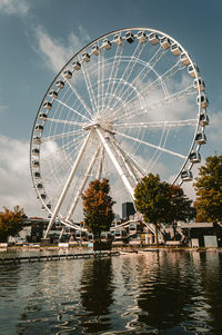 Ferris wheel by lake against sky