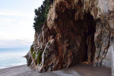 Rock formation on beach against sky