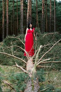 Woman standing on fallen tree in forest