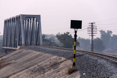 Information sign by railroad tracks against clear sky