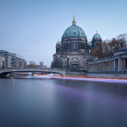 Light trail over river by berlin cathedral against clear sky at dusk