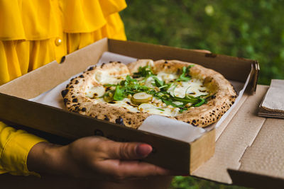 Midsection of woman holding pizza on table