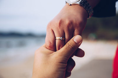 Cropped image of couple holding hands at beach