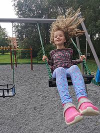 Girl sitting on swing in playground