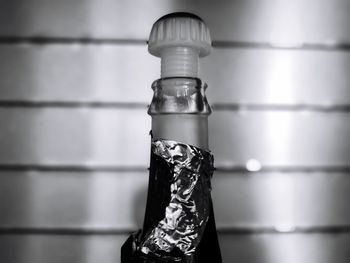 Close-up of glass bottle on table against wall