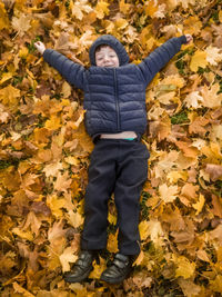 High angle view of boy lying on autumn leaves