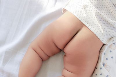 Midsection of baby lying down on bed at home