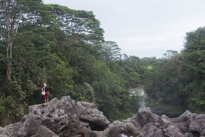 Woman standing on rock against sky