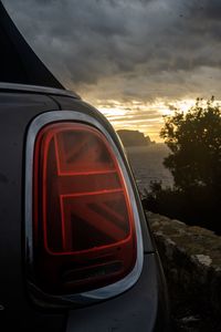 Close-up of red car against sky at sunset