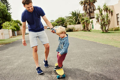 Father teaching skateboarding to son outdoors
