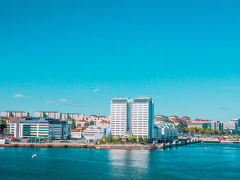 Sea by buildings against blue sky