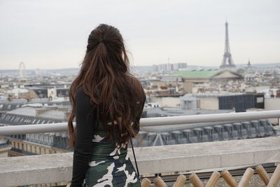 Rear view of woman looking at cityscape with eiffel tower at the background